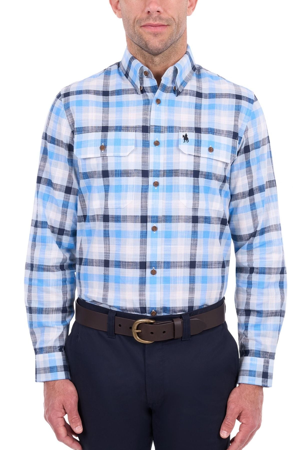 A man is wearing the Thomas Cook Jacob Shirt, a blue and white plaid button-down with chest pockets and a small embroidered logo on the left chest. The shirt is made from 100% cotton, and he has paired it with dark pants. His face is partially visible.