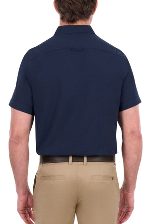 A man is shown from behind wearing the Thomas Cook Linen Short Sleeve Shirt in navy, paired with light tan pants. His arms are relaxed at his sides, and he has short brown hair.