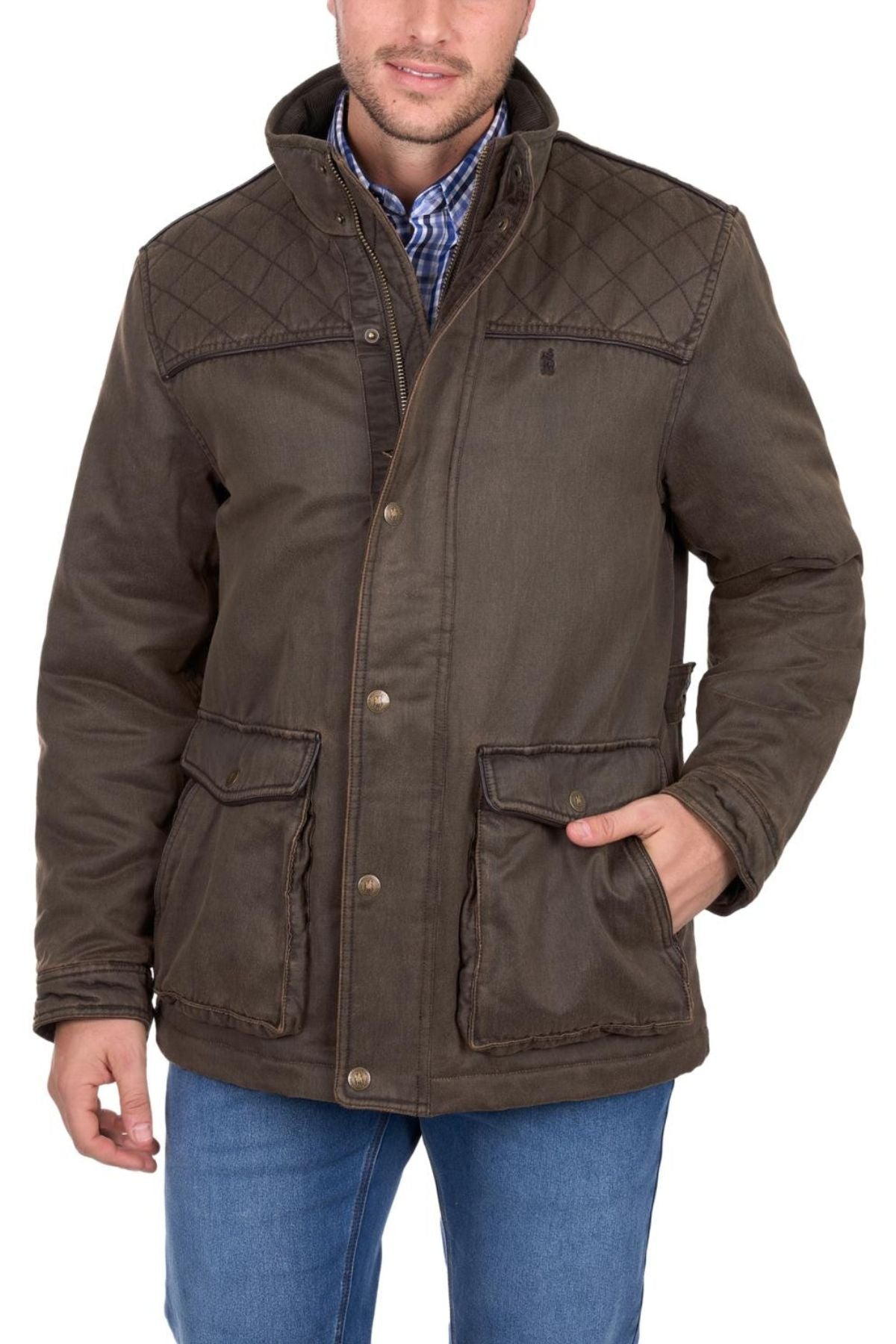 A man wears the Thomas Cook Marcus Jacket—a brown sherpa-lined faux oilskin coat with large front pockets—over a blue plaid shirt and blue jeans. Only his torso and lower face are visible, with one hand in his pocket.