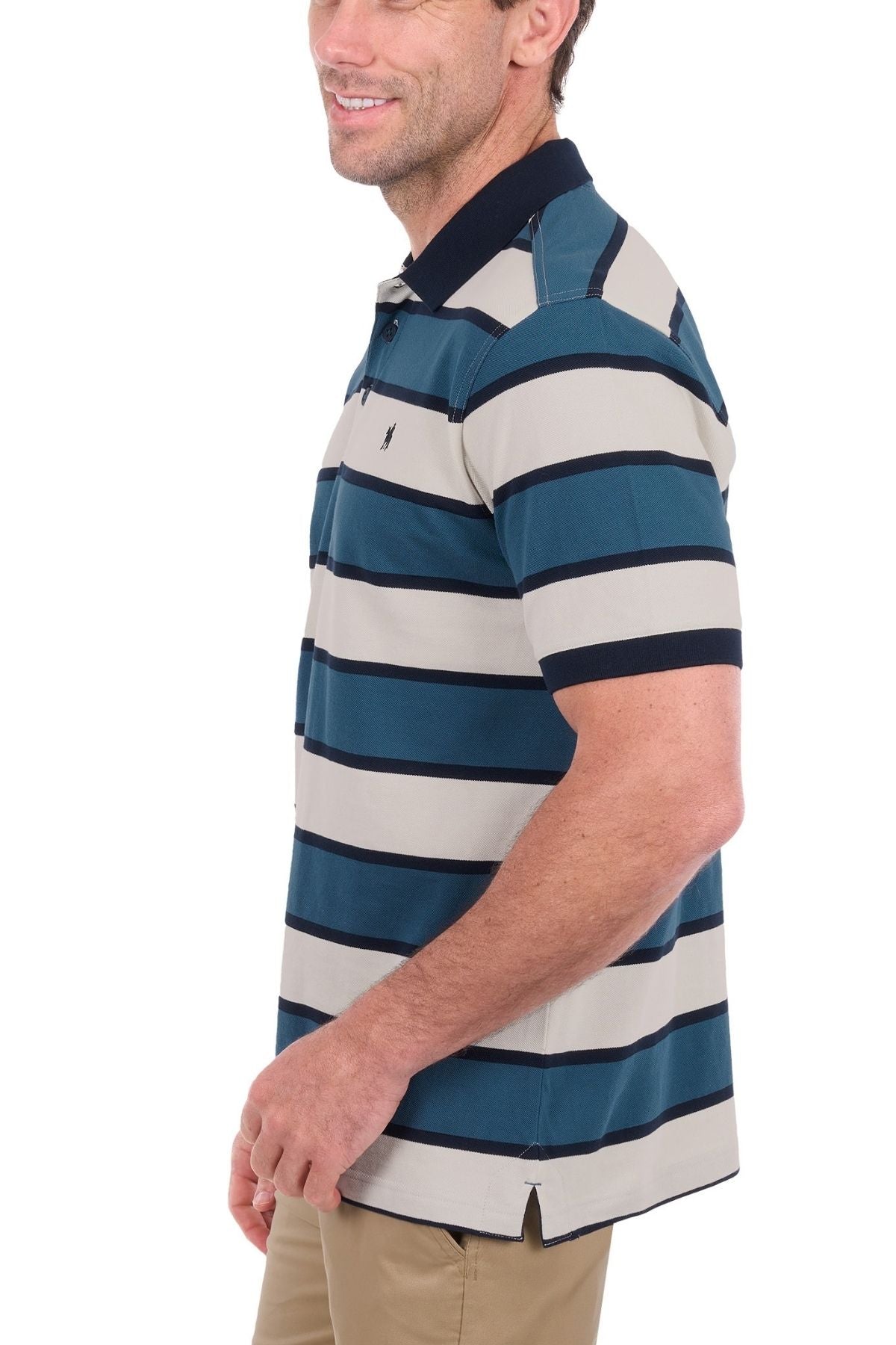 A man stands sideways and smiles while wearing the Thomas Cook Martin Polo—a short-sleeve, collared men’s polo featuring navy, beige, and white horizontal stripes crafted from soft cotton pique—paired with light khaki pants.