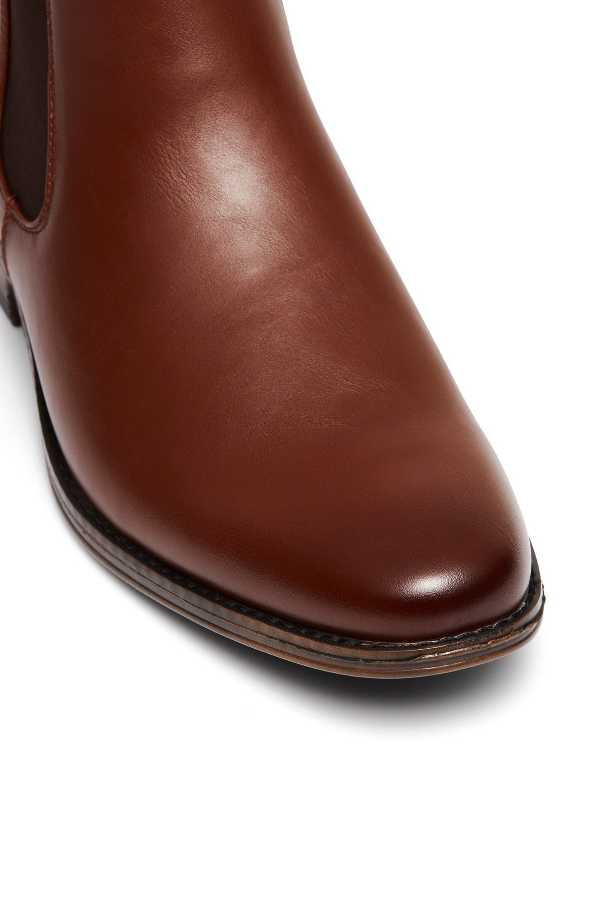 Close-up of a brown UNcut Canterbury Boot with a polished texture, featuring the front portion and side gussets. It highlights the sleek, shiny finish and detailed stitching.