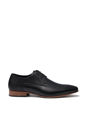 The UNcut Chartwell Shoe is ideal for formal events, featuring a sleek black leather design with an embossed upper panel and brown wooden sole. Its lace-up closure enhances the shoe, shown against a plain white background to highlight its elegant side profile.