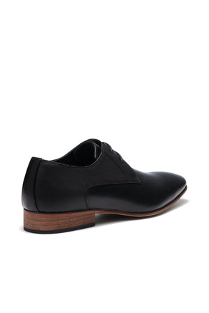 Introducing the UNcut Chartwell Shoe—ideal for formal events. This black dress shoe features a sleek design with an embossed upper panel and contrasting brown sole, complemented by a low heel, laces, and subtle textured pattern for added sophistication.