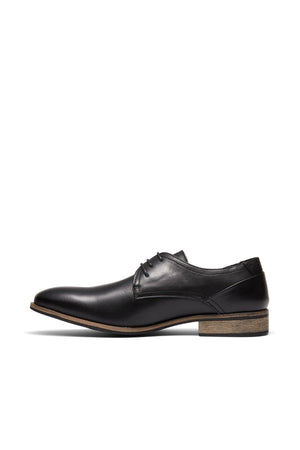 The UNcut Rhine Shoe in black features laces, a low heel, and a light brown sole. Displayed in side profile on a white background, it's an ideal pick for formal occasions.