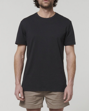A person wearing a Black Hard Yakka Core Tee, made from Australian Cotton, and beige shorts stands against a plain white background. The person's face is not visible.