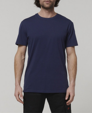 A man with short dark hair is seen against a plain background, dressed in a Hard Yakka Core Tee crafted from 100% Australian cotton and black pants. The image displays only his upper body.