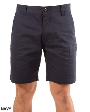 A person wears UNIT Ignition Stretch Shortβknee-length, navy blue work shorts made from durable stretch fabric with button and zipper closure, front and side pockets. "NAVY" appears in the bottom left corner.