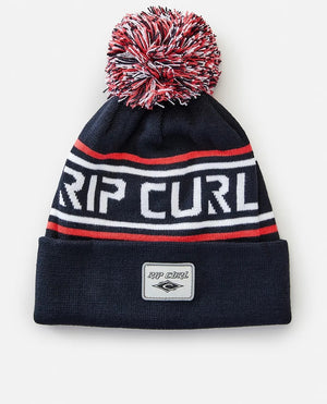 The Rip Curl Fade Out Tall Beanie is a chic black acrylic hat featuring a vibrant red, white, and black pom-pom. It showcases "RIP CURL" in white with red and white stripes and includes a small patch of the iconic Rip Curl logo in front.