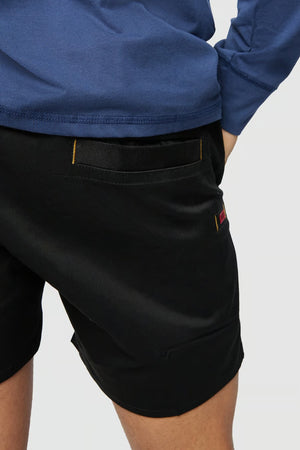 A person wearing a blue long-sleeve top and the CAT Short Haul Short with yellow stitching is posing with their hand on their hip, focusing on the back cargo pocket area of the shorts.