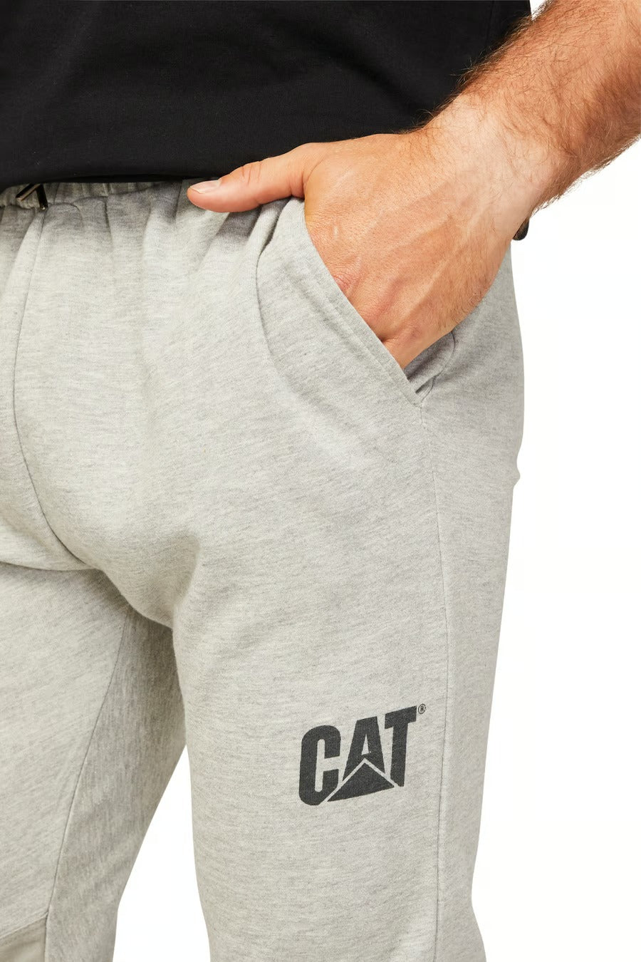 A person wearing CAT Track Pant with one hand in a pocket. The durable light gray pants display a "CAT" logo on the upper left thigh and are paired with a black shirt against a plain white background.