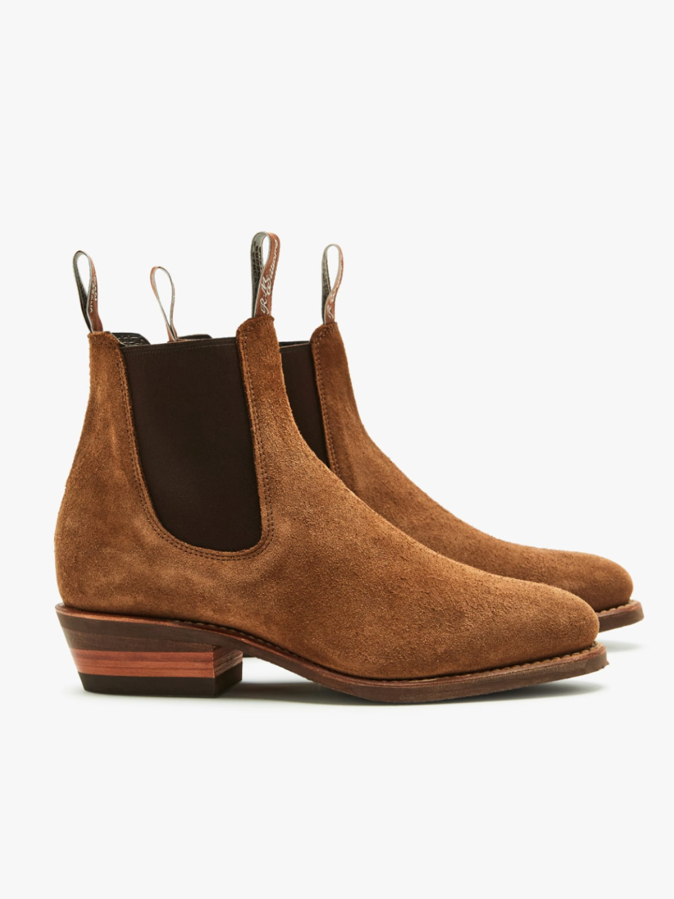 The RM Williams Lady Yearling Suede Rubber Sole Boot features brown suede, black elastic side panels, and front and back pull tabs. These chic Chelsea boots come with a wooden sole and block heel, making them suitable for both casual and stylish outfits.