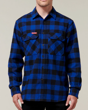 A person is wearing a Hard Yakka Check Flannelette Shirt in blue and black with buttoned chest pockets and a small red patch on the left chest. This durable shirt, crafted from Cotton Twill, is buttoned up and provides UPF 50+ sun protection. The person is shown from the shoulders to the waist against a neutral background.