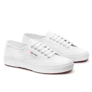 The Superga Cotu Classic Sneaker features a white canvas upper, paired with white laces and a distinctive red and blue logo on the side. With a classic, simple design, these low-top sneakers sit atop a white rubber sole.