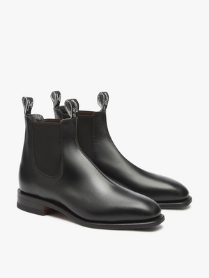 A pair of sleek, black RM Williams Dynamic Flex Craftsman Boots crafted from yearling leather, featuring pull tabs with white text detailing and elastic side panels. These boots showcase a smooth finish and a low heel, designed for both style and comfort.