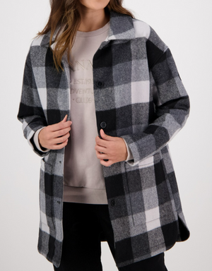 A person is adjusting a Swanndri Becroft Wool Coat, a stylish, comfortable plaid in black, white, and gray over a beige sweatshirt. This merino wool blend comes with a collar and buttons down the front. Their face is hidden against a plain light background.