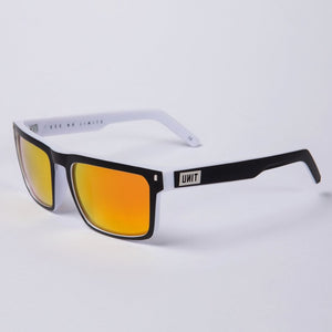 The UNIT Primer Polarised Eyewear features a stylish black and white lightweight frame with reflective orange lenses. These sunglasses offer UV protection and have the word "UNIT" printed on the side of the right arm, and are photographed against a plain white background.