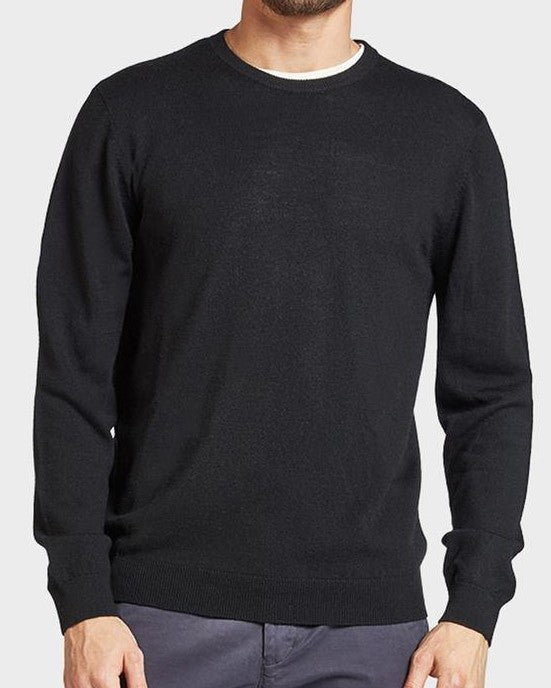 A man wearing the Academy Brand Academy Merino Crew in plain black paired with dark gray pants. The background is a light gray color. His head is partially out of the frame, and his hands are relaxed at his sides, showcasing the comfortable, casual jumper made from Australian Merino Wool.