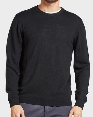 A man wearing the Academy Brand Academy Merino Crew in plain black paired with dark gray pants. The background is a light gray color. His head is partially out of the frame, and his hands are relaxed at his sides, showcasing the comfortable, casual jumper made from Australian Merino Wool.