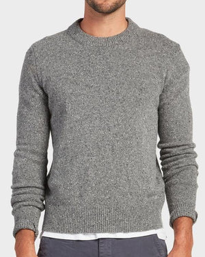 A man wears the Academy Brand Shoreditch Crew Knit in grey over a white shirt with dark pants, standing against a plain light background. His head is partially out of frame.