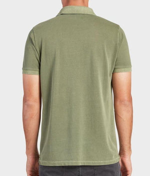 A person wearing an Academy Brand Academy Polo in light green and dark pants is shown from the back. The comfortable cotton pique fabric offers a relaxed feel as the person's arms rest by their sides against a plain light gray background.