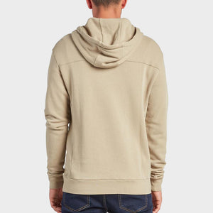 A person wearing a comfortable beige Academy Brand Boston Hoodie and dark blue jeans is shown from the back, standing against a plain white background.