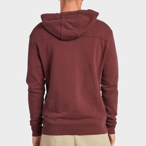 A person is shown from the back wearing a maroon Academy Brand Boston Hoodie and beige pants, standing against a plain light gray background.