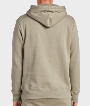 A person wearing the Academy Brand College Hoodie in light olive green, shown from the back with the hood down and arms relaxed, displays a laid-back, casual vibe against a plain background.