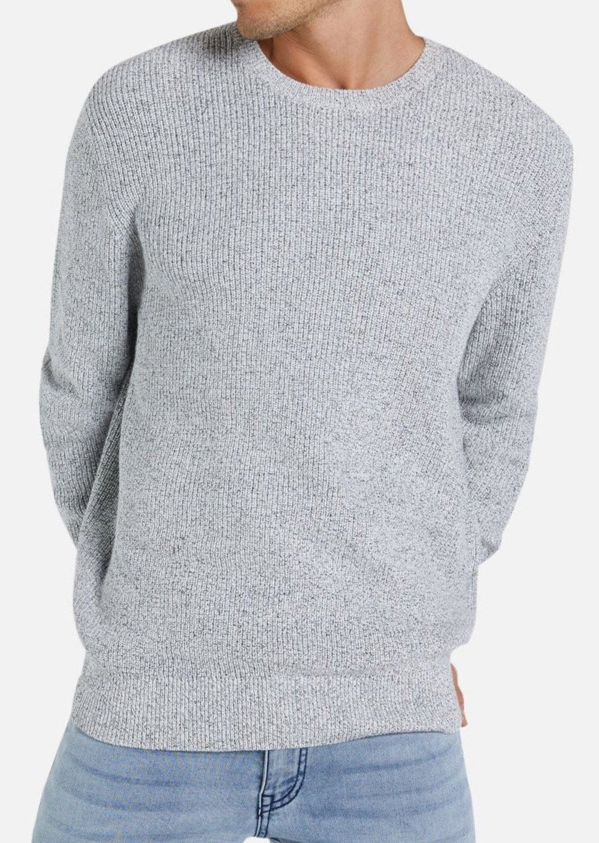 Someone wearing the Industrie The Kingston Knit, a textured gray crew neck sweater made from 100% cotton, and light blue jeans stands against a plain white background with hands behind their back, face partially out of view.