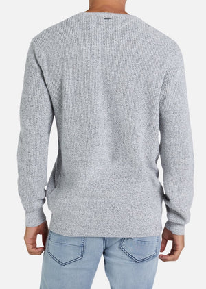 Someone models the Industrie The Kingston Knit, a light gray long-sleeve sweater with waffle knit detail, paired with light blue jeans and shown from behind against a plain white background.