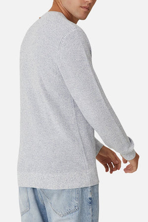 A man is shown from the back, turning slightly left, wearing the Industrie The Kingston Knit in light gray (100% cotton, waffle knit) with light blue jeans against a plain white background.