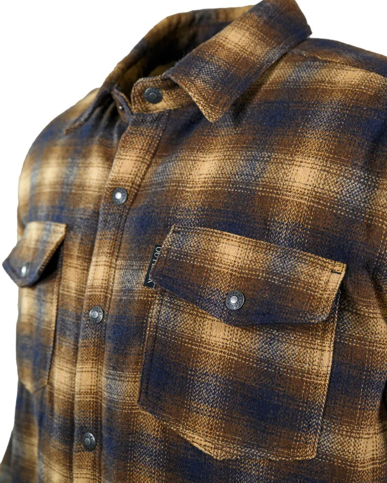 The Outback Arden Jacket, in a brown, beige, and dark blue plaid pattern, offers the warmth of a jacket with its Polyester/Wool blend. It includes two front chest pockets with button flaps and a visible button near the collar.