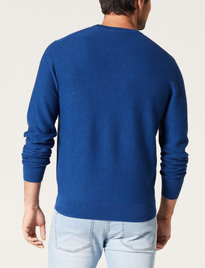 A man is seen from behind, wearing the Blazer Mason Cotton Textured Crew Neck jumper in royal blue with light blue jeans, standing against a plain light background.