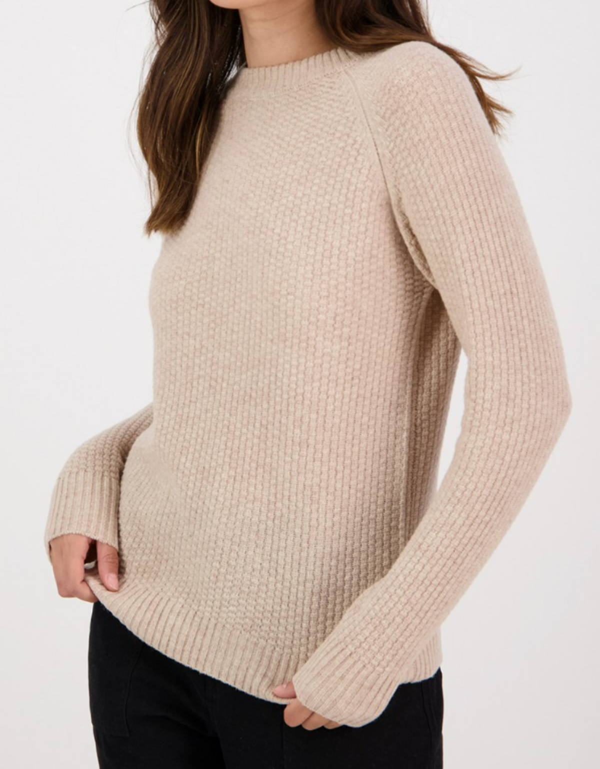 A person models the Swanndri Hayes Park Waffle Knit Crew, a beige long-sleeve sweater, paired with black pants and shown from the shoulders down against a plain white background. Their hands are slightly tucked into the sleeves.