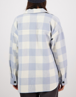 A person is shown from the back wearing a Swanndri Anchorage Wool Shirt Jacket in light blue and white check, with long sleeves and black buttons, against a plain white background.