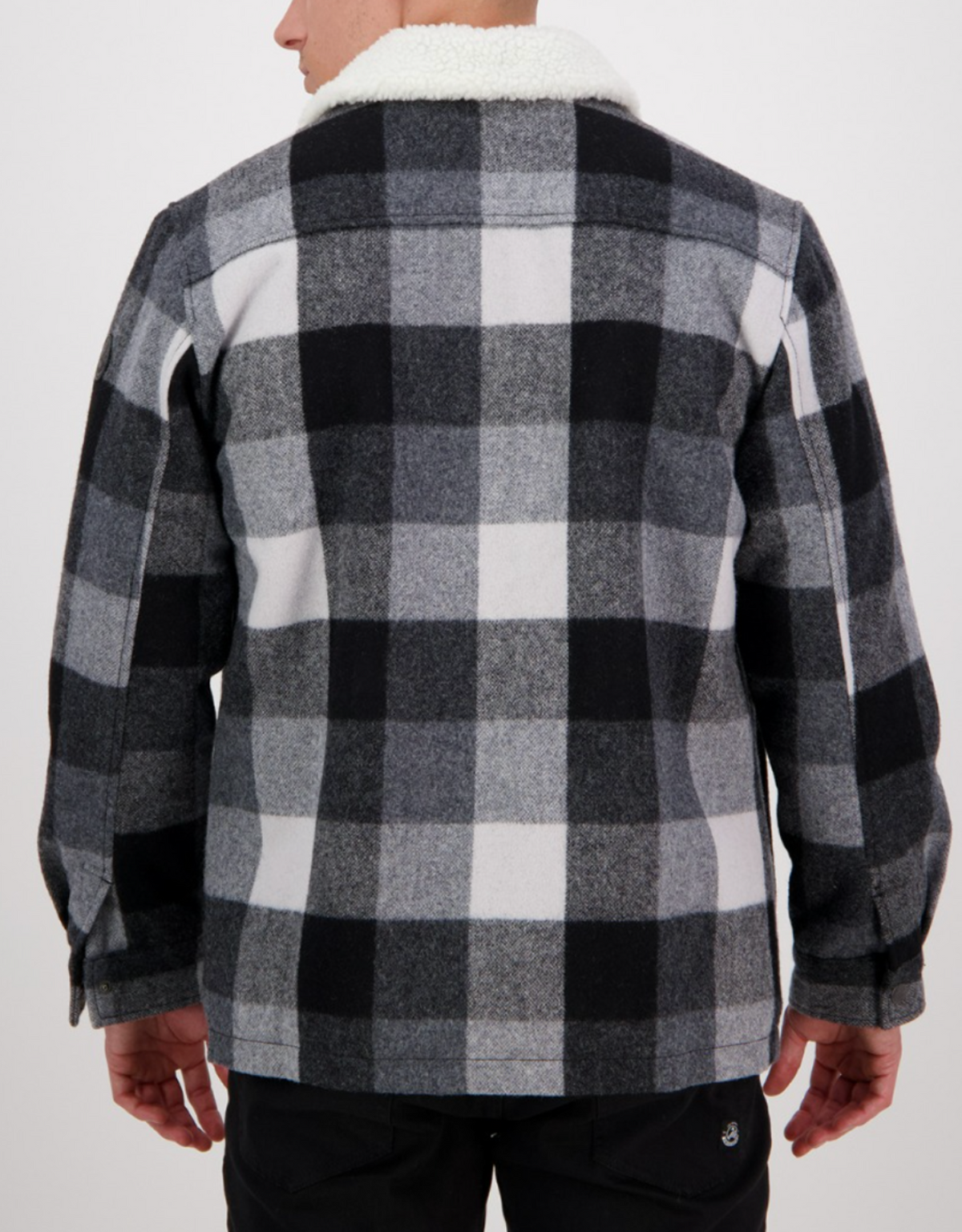 A person is seen from behind wearing the Swanndri Kaituna Sherpa Lined Jacket in black, white, and grey plaid with a white sherpa collar. The warm sherpa lining pops against the simple, light background.