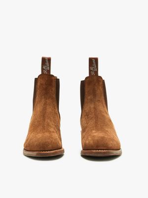 The RM Williams Lady Yearling Suede Rubber Sole Boot features brown suede, dark elastic side panels, and handy pull tabs. Displayed on a light background, these stylish boots have a subtle block heel with a forward-facing design for a classic yet modern look.
