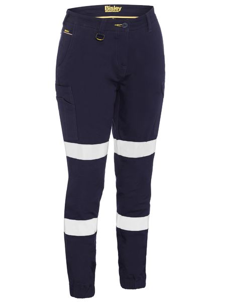 The Bisley Women's Taped Cuffed Cargo Pant in dark blue features durable cotton fabric, white reflective tape above and below the knees, side pockets, and a yellow zipper for high visibility and safety.