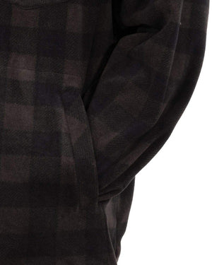 A close-up shows the Outback Mens Big Shirt, a dark plaid mid-weight with 100% polyester fabric in a black and brown checkered pattern. Only the garment and a partial arm are visible, with one hand tucked into a side pocket.
