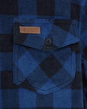 Close-up of the Outback Men's Big Shirt showcasing its blue and black checkered mid-weight design, a chest pocket with a button, adjustable button wrist cuffs, and a small brown leather tag inscribed with "Outback" along with additional small text.