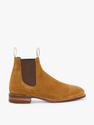 An RM Williams Comfort Suede Craftsman Boot, made from premium tan suede leather, is showcased against a white background. The boot features elastic side panels, front and back pull tabs, a wooden heel, and a smooth toe design. These Handcrafted Australia boots are designed for both style and comfort with their rubber sole.
