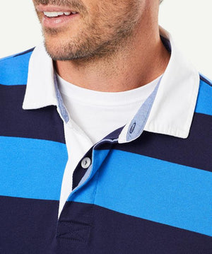 Close-up shot of a man wearing the Gazman Block Stripe Rugby, featuring blue and navy stripes with a contrasting white collar over a white undershirt. The cotton fabric drapes comfortably, highlighting its regular fit. The man has light facial hair, with only the lower part of his face visible.