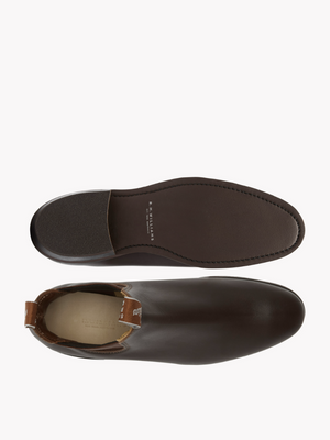 Top-down view of RM Williams Adelaide Rubber Sole Boots in dark brown. One boot is shown from the top, and the other displays its sole with edge stitching for a smart-casual look. Both boots feature a tan pull tab at the back.
