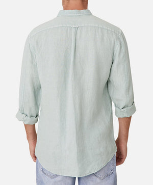 A person is wearing the Industrie The Tennyson Linen Shirt in light green, made of 100% linen. The long sleeves are rolled up to show the marle texture, paired with light blue jeans against a plain white background. Viewed from the back.