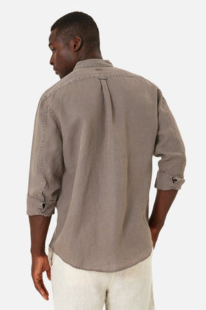 Seen from behind, a person with short black hair wears the Industrie The Tennyson Linen Shirt, a relaxed fit, long-sleeve gray button-down with rolled-up sleeves made from 100% linen. It pairs effortlessly with their light-colored pants against the plain white background.