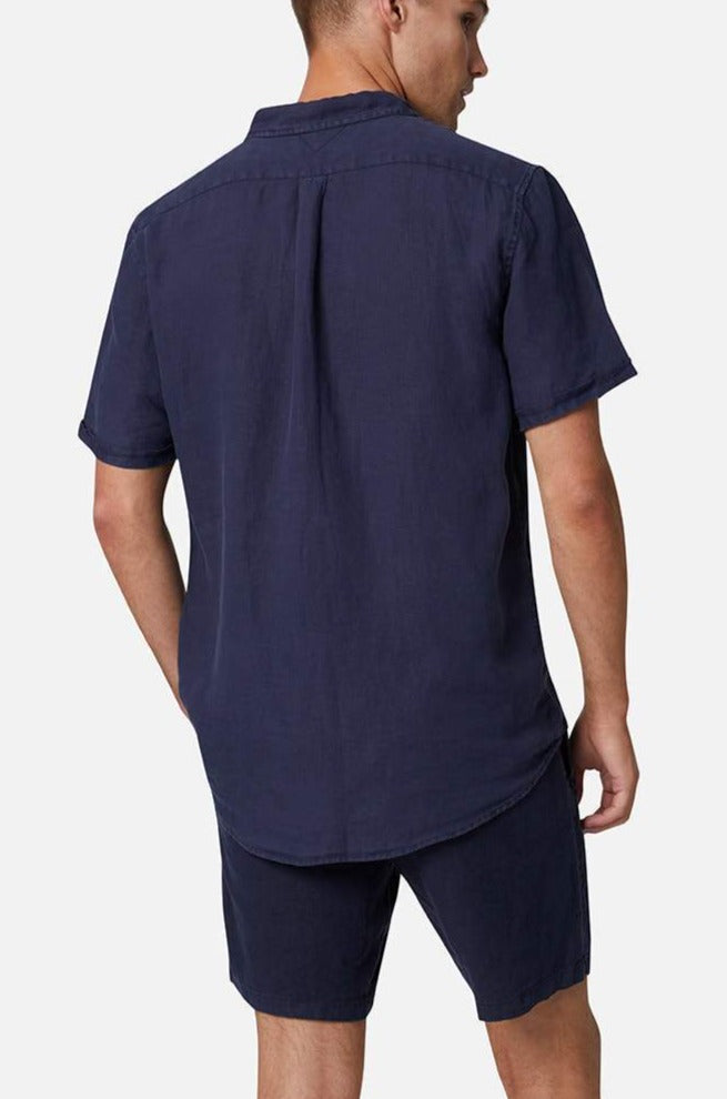 A person in an Industrie The Tennyson Linen Short Sleeve Shirt, relaxed fit and dark blue, stands with their back turned. They wear matching shorts against a plain white background.