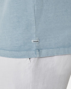 Close-up of a person in an oversized light blue Industrie The Del Sur Tee and white pants, featuring a small tag near the hem that adds a subtle touch to its relaxed style.