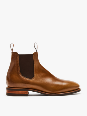 The RM Williams Comfort Craftsman Boot is a brown pull-up leather Chelsea boot with elastic side panels, pull tabs, and a low stacked heel. It boasts a sleek, polished finish and durable rubber sole for a classic yet stylish appearance with enhanced durability.