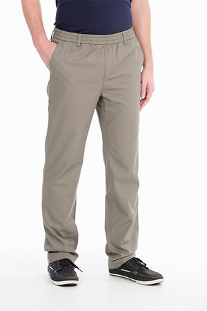 A person wearing light brown Bob Spears Pull On Pant with an elastic waistband and hands partially in pockets. The comfortable pull-on pants are paired with a dark navy shirt tucked in. The individual is also wearing black casual shoes with white soles, all set against a plain white background.