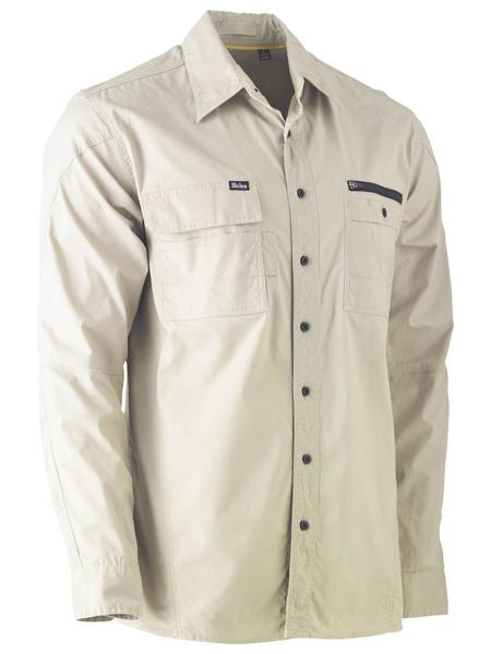 The Bisley Flex & Move Utility Work Shirt in beige is a long-sleeve, button-up design featuring two chest pockets, one adorned with a small dark flap and zipper. This shirt includes a classic collar and black buttons down the front, providing SPF 50+ protection for extended periods in the sun.
