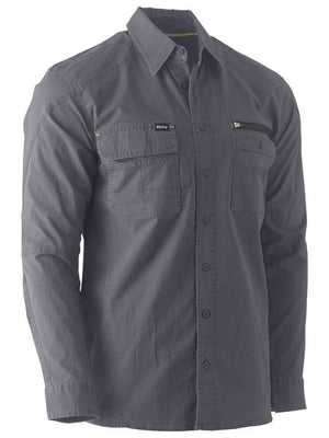 The Bisley Flex & Move Utility Work Shirt, in gray, is a long-sleeve button-up shirt equipped with two chest pockets. The left pocket features a flap and button closure, while the right pocket includes a zipper. Designed for both style and practicality, this shirt offers SPF 50+ protection and rugged durability, making it ideal for outdoor tasks.
